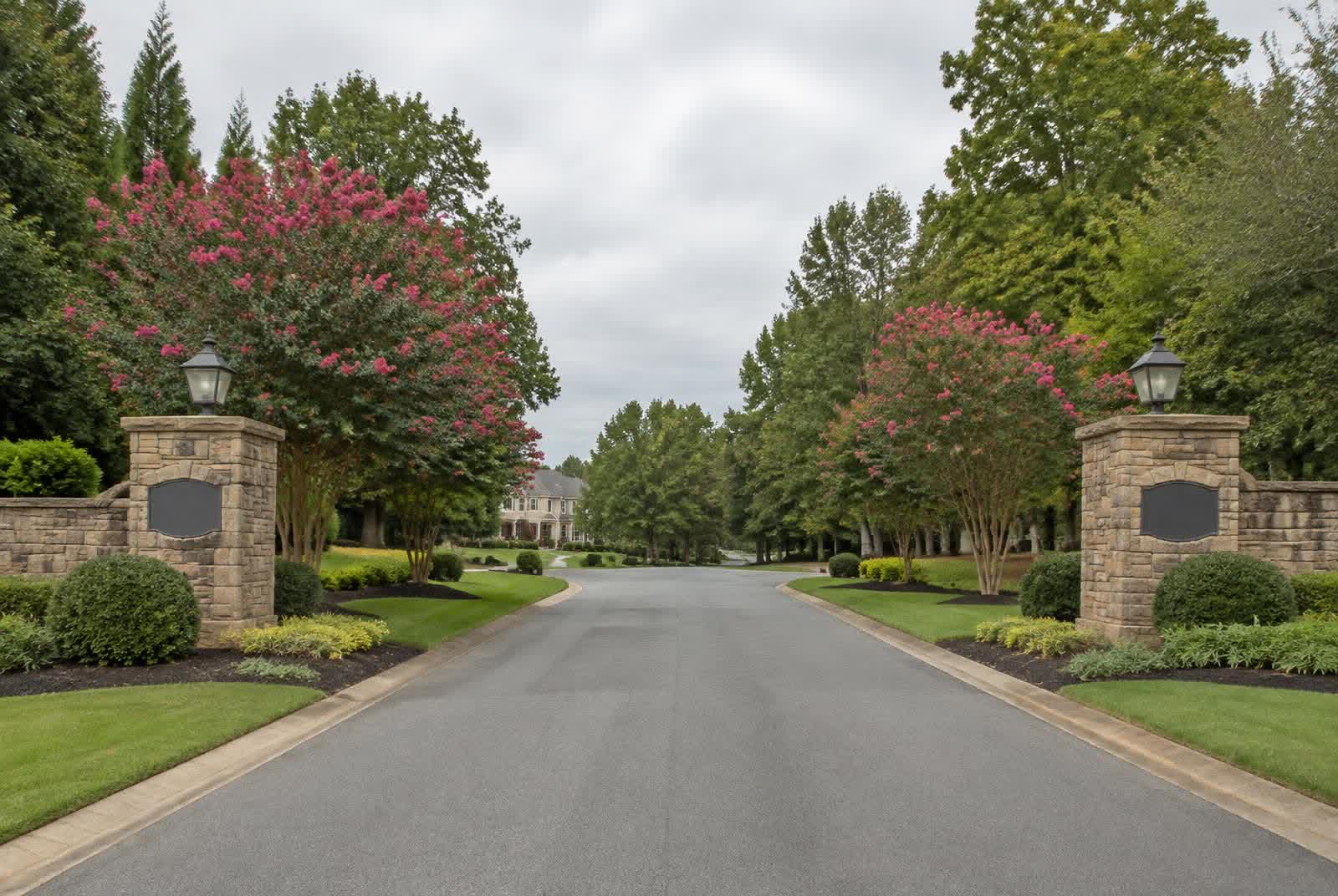 Stone entry pillars and tree-lined entrance drive of an established custom-home neighborhood in Marvin, North Carolina