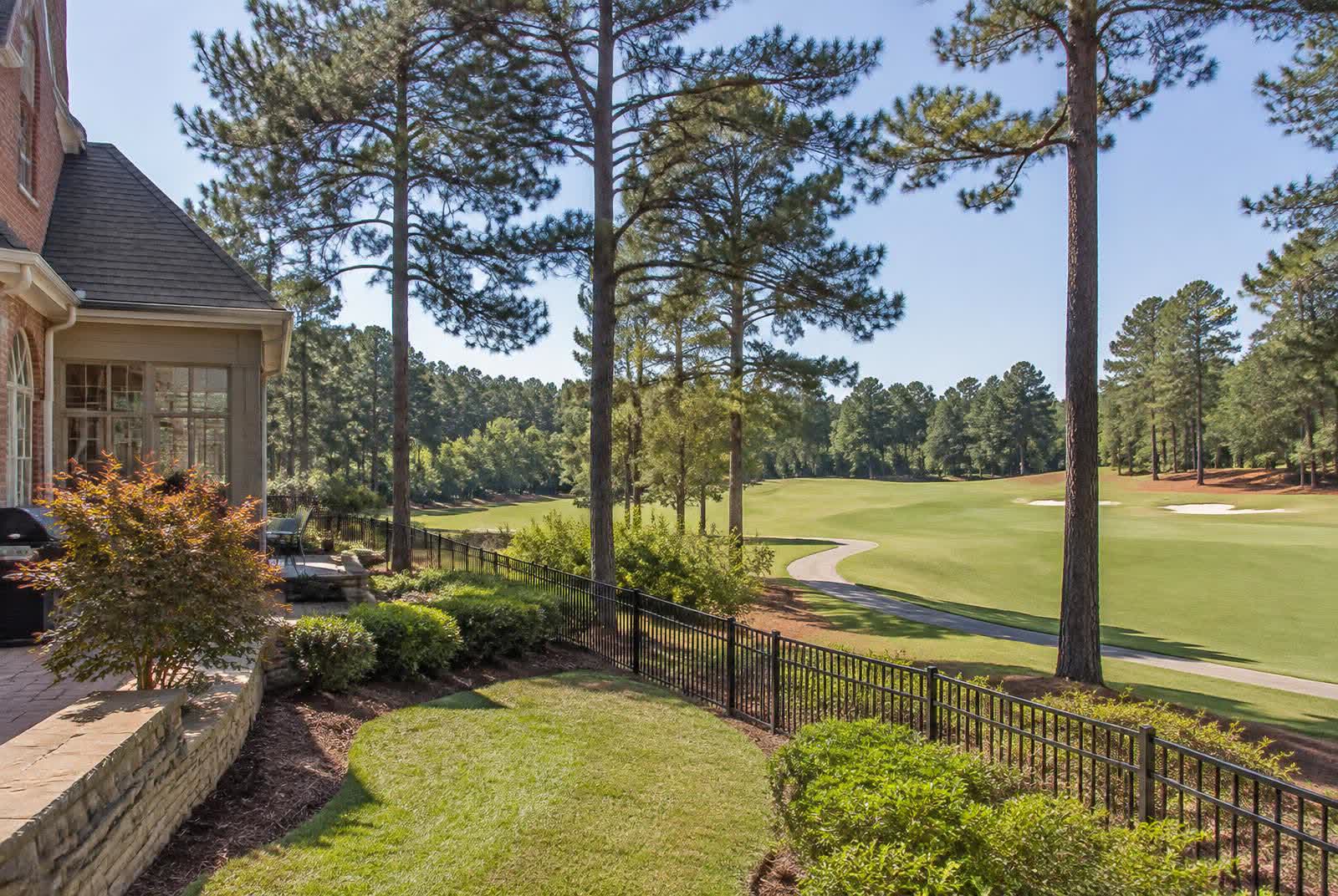 Luxury home backing onto a manicured golf fairway lined with tall pines near Marvin, North Carolina