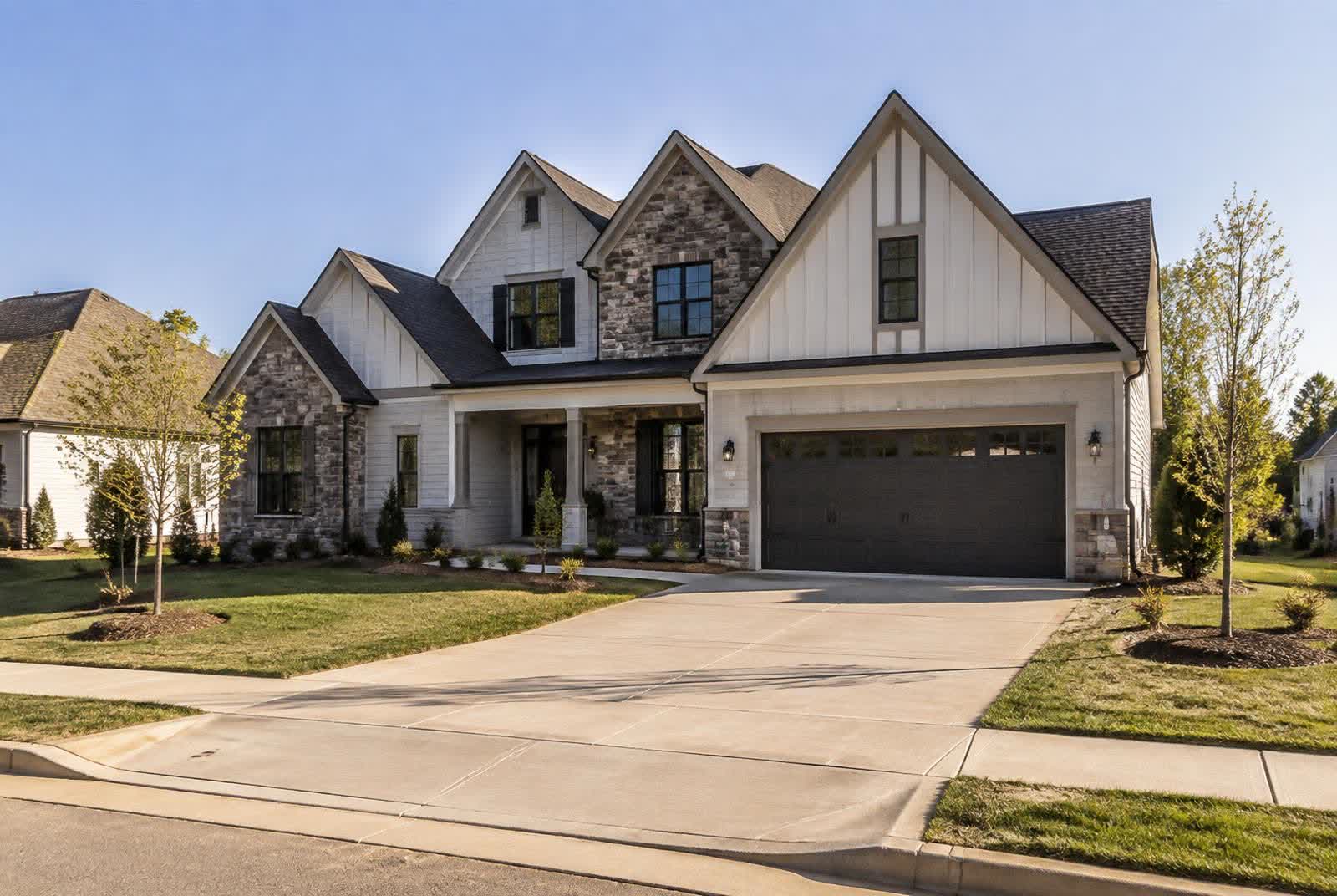 Newly built transitional home with stone and board-and-batten detail on a young street in Marvin, North Carolina