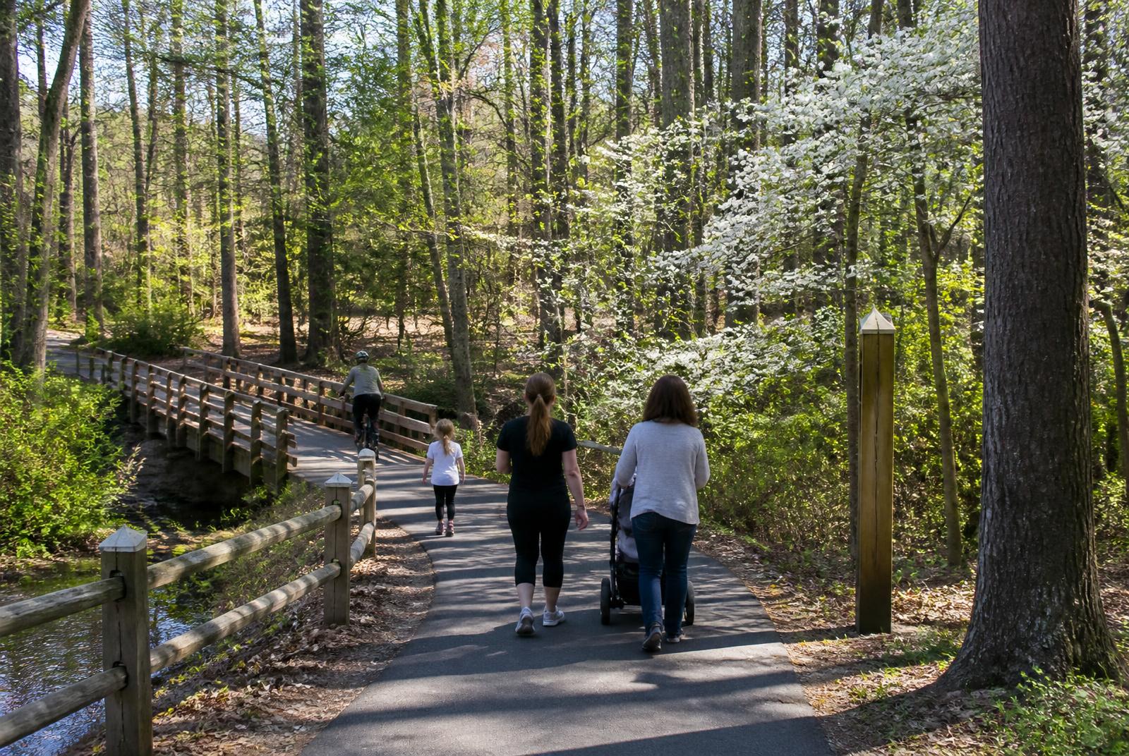 Families walking the paved greenway trail through the woods in Marvin, North Carolina